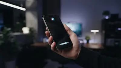 Close-up de um iPhone exibindo interface da Siri em um ambiente moderno e minimalista com luzes de LED suaves.