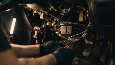 Detalhe de módulo eletrônico instalado sob o painel de um carro popular durante manutenção automotiva técnica