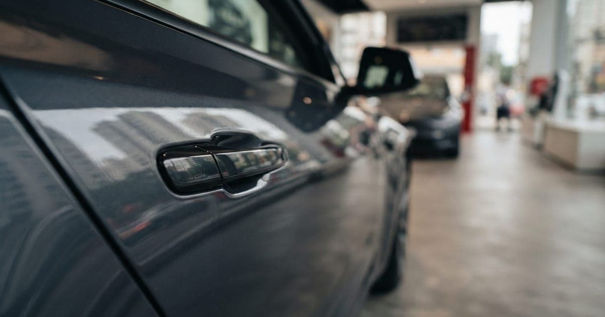 Detalhe da maçaneta de uma porta de carro elétrico Tesla com reflexo urbano em uma concessionária moderna