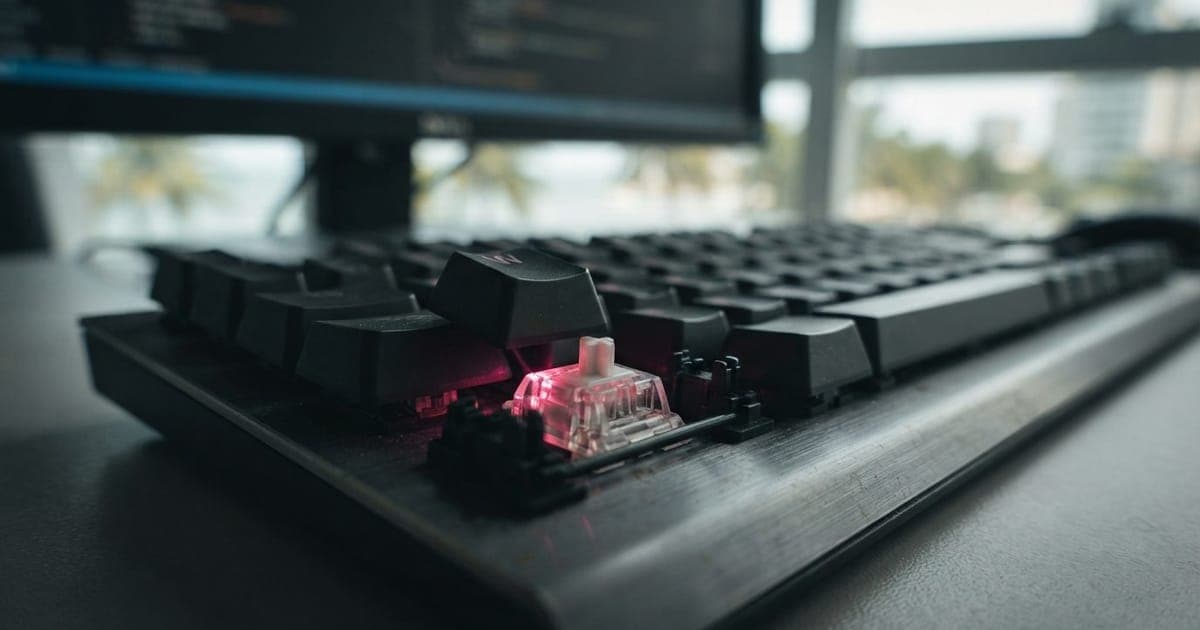 Close-up de teclado mecânico com switch óptico iluminado por luz infravermelha em ambiente de escritório