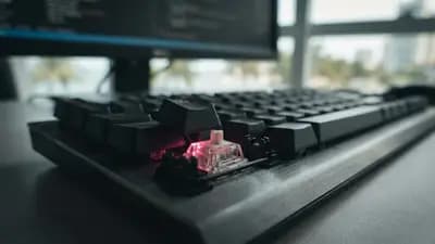 Close-up de teclado mecânico com switch óptico iluminado por luz infravermelha em ambiente de escritório