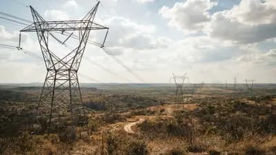 Linhas de transmissão de alta tensão sobre paisagem árida sob céu ensolarado simbolizando a gestão de infraestrutura de energia.